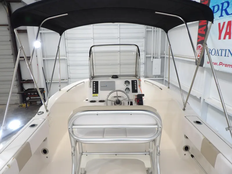 Slide: The Image of 2020 Robalo R180 boat interior with steering console and canopy in a showroom. - 15