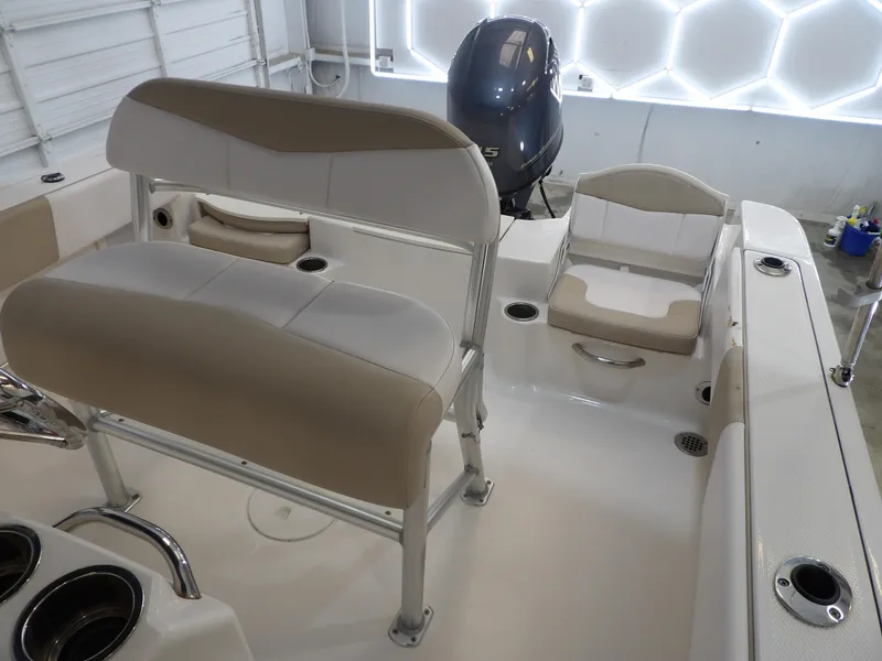 Slide: The Image of 2020 Robalo R180 boat interior with seating and motor in a garage setting. - 20