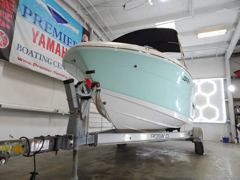 Slide: The Image of 2020 Robalo R180 boat on trailer in showroom, Premier Yamaha banner visible. - 5