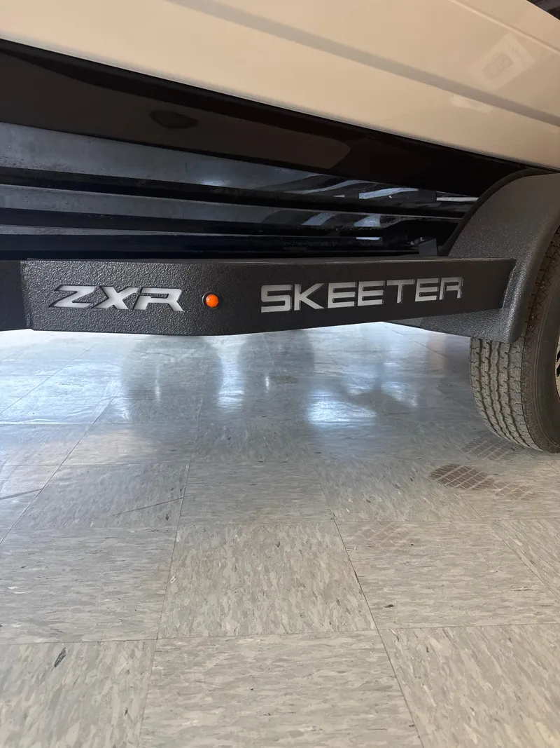 Slide: The Image of 2025 Skeeter ZXR20SE trailer detail with logo and tire on showroom floor. - 3