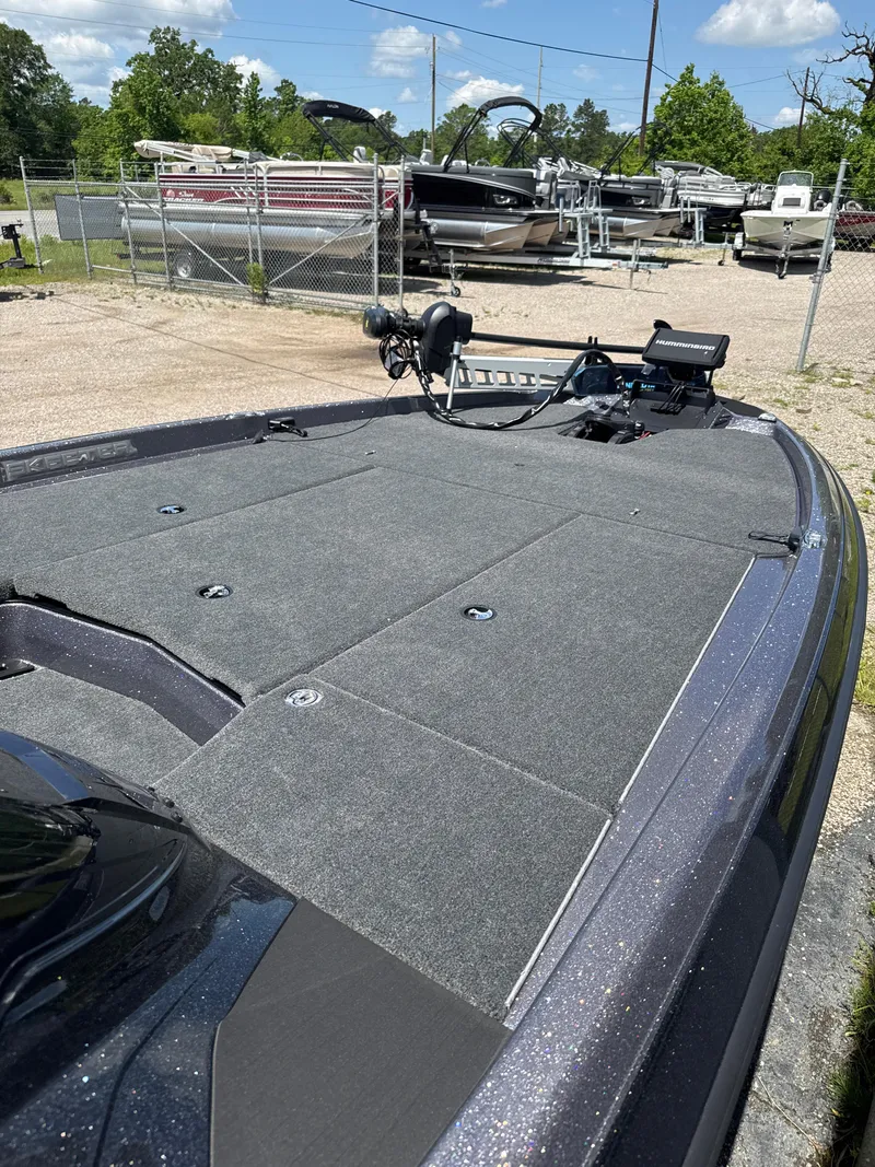 Slide: The Image of 2025 Skeeter ZXR21SE boat deck with fishing equipment, parked near other boats. - 16