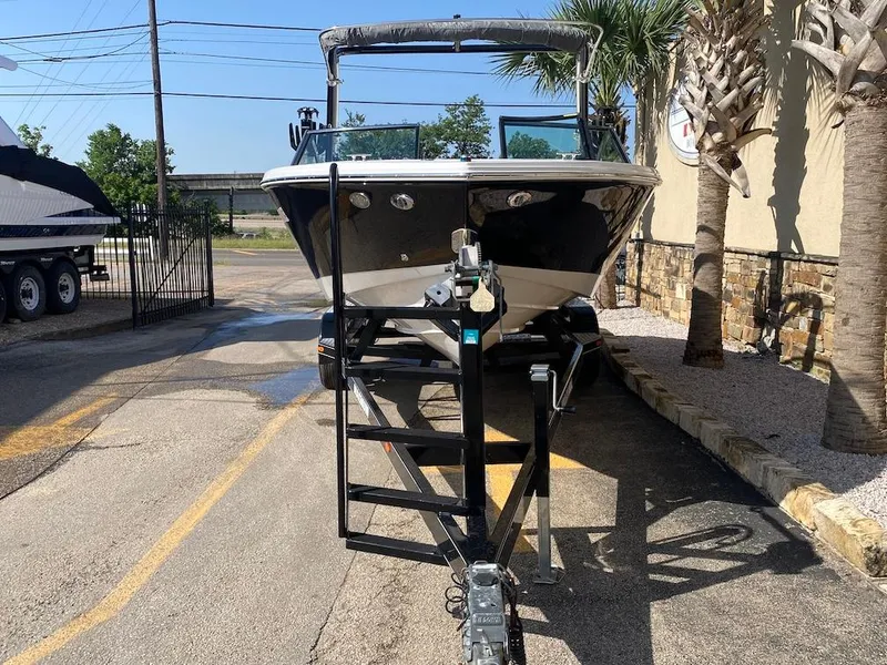 Slide: The Image of 2018 Cobalt CS23 Surf boat on trailer, parked outdoors near palm trees. - 3