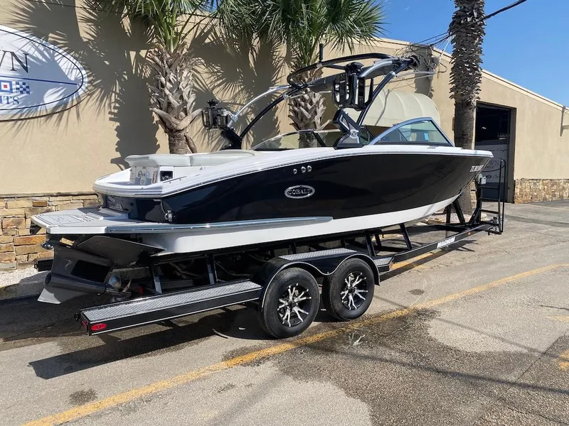 Slide: The Image of 2018 Cobalt CS23 Surf boat on trailer, parked outdoors near palm trees. - 7