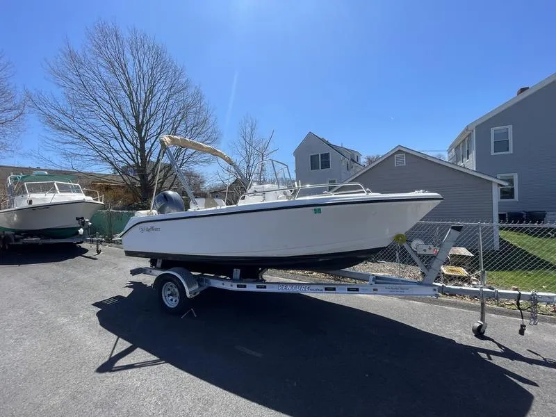Slide: The Image of 2022 Edgewater 170CC boat on trailer, parked in residential area under clear blue sky. - 5