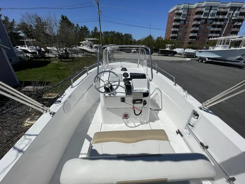 Slide: The Image of 2022 Edgewater 170CC boat interior with steering console and seating, parked outdoors. - 8