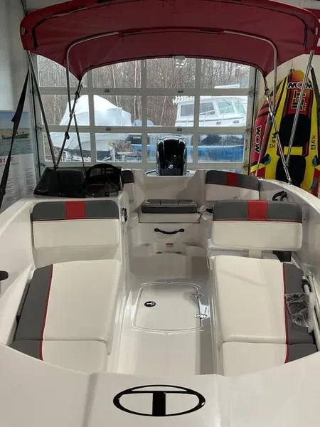 Slide: The Image of 2025 Tahoe T16 boat with red canopy and spacious seating in showroom. - 2