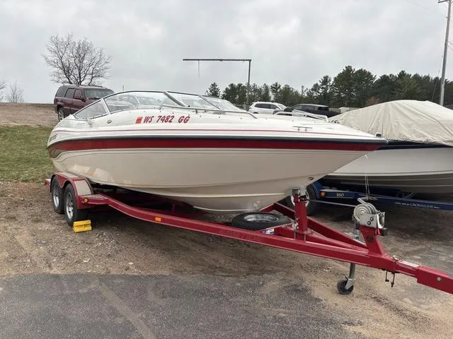 Slide: The Image of 2002 Ebbtide 210 Campione boat on red trailer, parked outdoors. - 2