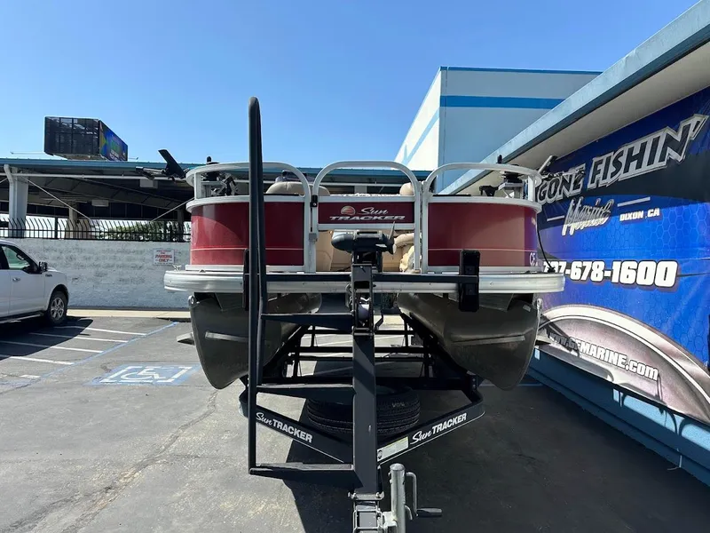 Slide: The Image of 2019 Sun Tracker Bass Buggy 18 DLX pontoon boat on trailer in parking lot. - 2