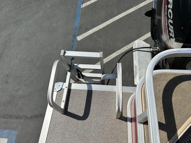 Slide: The Image of 2019 Sun Tracker Bass Buggy 18 DLX boat ladder and motor in parking lot. - 28