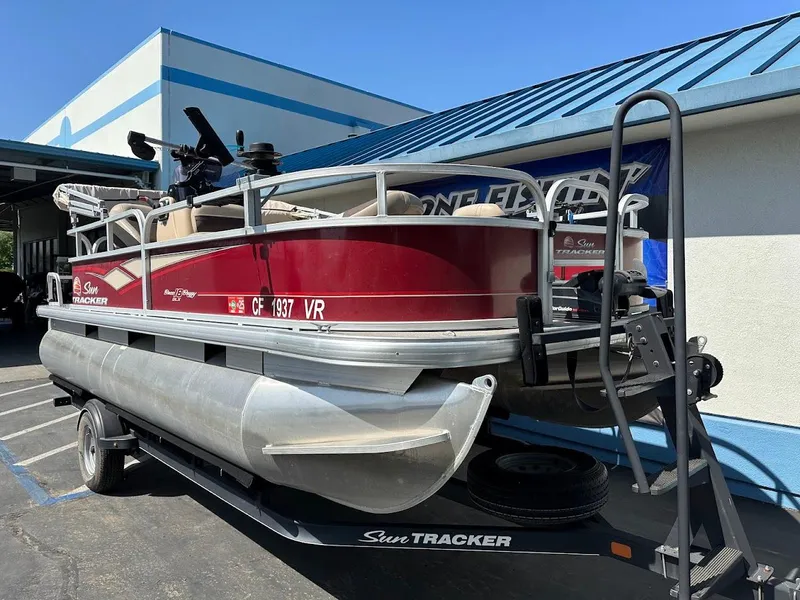 Slide: The Image of 2019 Sun Tracker Bass Buggy 18 DLX pontoon boat on trailer, parked outdoors. - 4