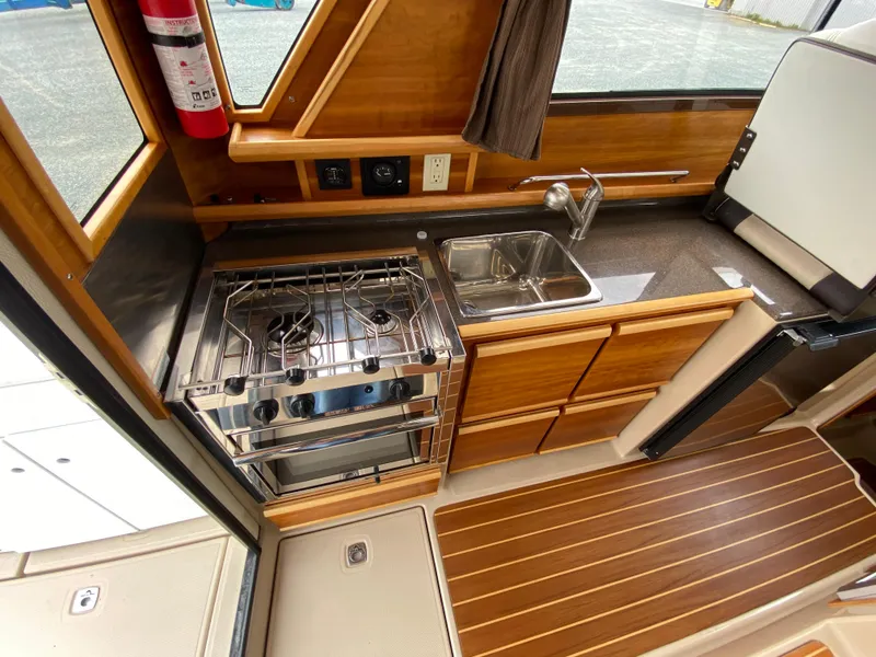 Slide: The Image of 2017 Cutwater C-28 boat kitchen with stove, sink, and wooden cabinetry. - 10