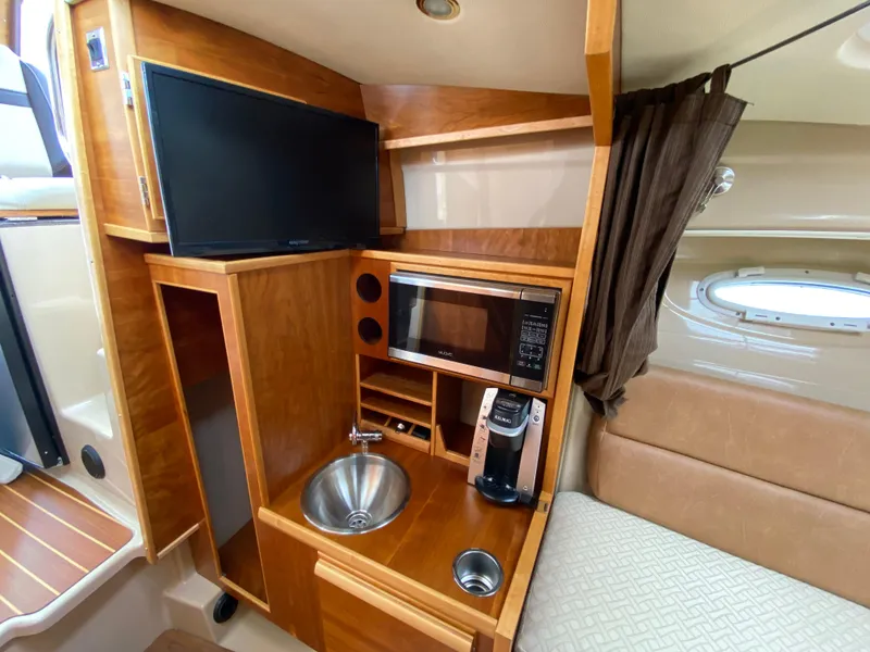 Slide: The Image of 2017 Cutwater C-28 interior with kitchenette, TV, microwave, and sink. Cozy and functional boat cabin. - 16