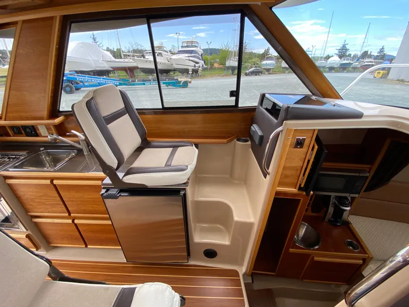 Slide: The Image of 2017 Cutwater C-28 interior with seating, kitchenette, and window view of marina. - 6