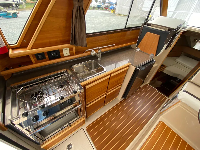 Slide: The Image of 2017 Cutwater C-28 boat interior with modern kitchen, stove, sink, and wood finish. - 8