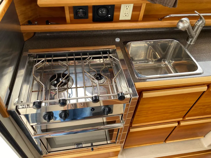 Slide: The Image of 2017 Cutwater C-28 boat kitchen with stove, sink, and wooden cabinetry. - 9