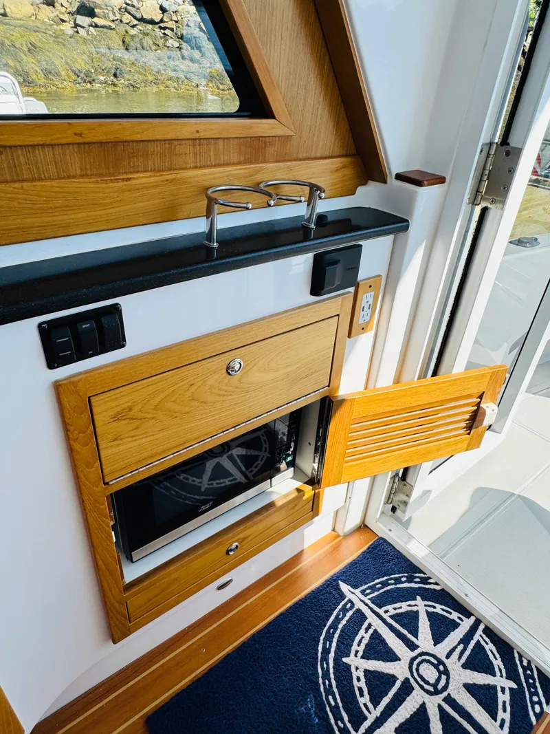 Slide: The Image of 2024 True North 34 Outboard Express interior with wooden cabinetry and nautical-themed decor. - 10