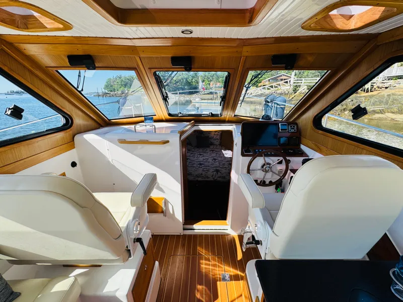 Slide: The Image of Interior of 2024 True North 34 Outboard Express boat with wooden accents and steering wheel. - 13