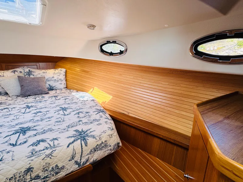 Slide: The Image of 2024 True North 34 Outboard Express cabin with wood paneling and nautical-themed bedding. - 17