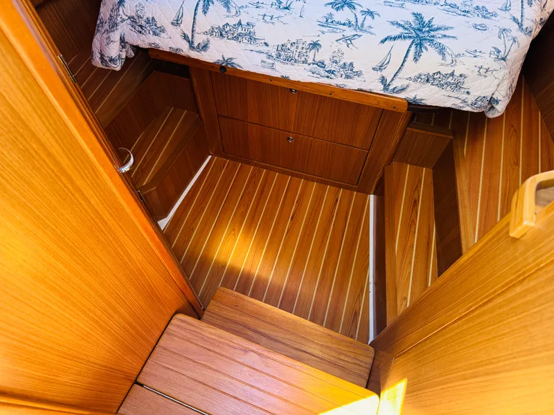 Slide: The Image of 2024 True North 34 Outboard Express cabin interior with wooden flooring and nautical-themed bedding. - 19