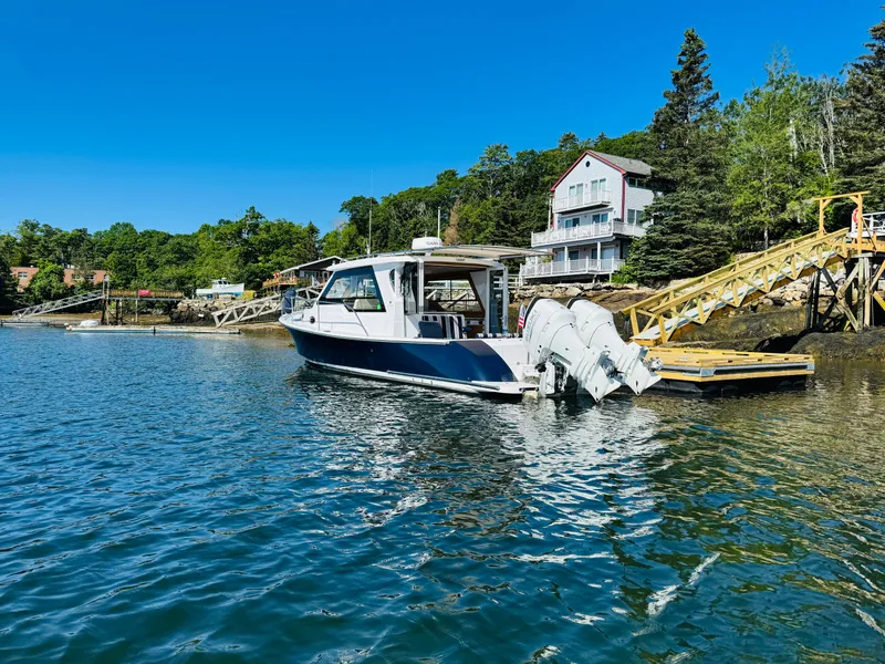 Slide: The Image of 2024 True North 34 Outboard Express docked by scenic waterfront homes. - 2