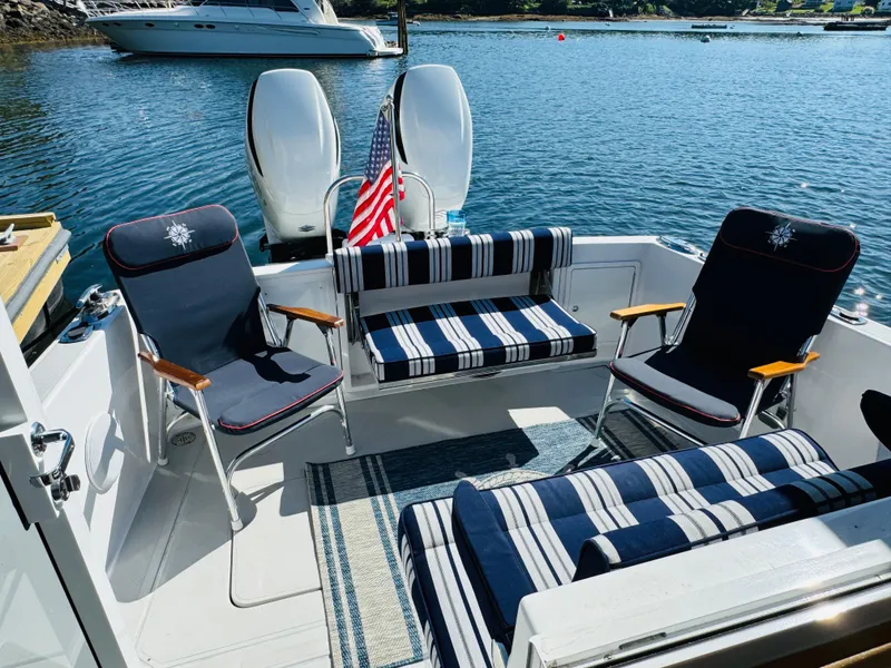 Slide: The Image of 2024 True North 34 Outboard Express boat with striped seating and American flag on a sunny day. - 20