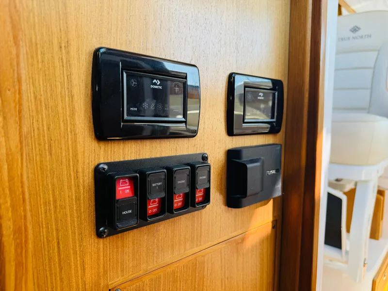 Slide: The Image of 2024 True North 34 Outboard Express control panel with switches and displays on wooden surface. - 30