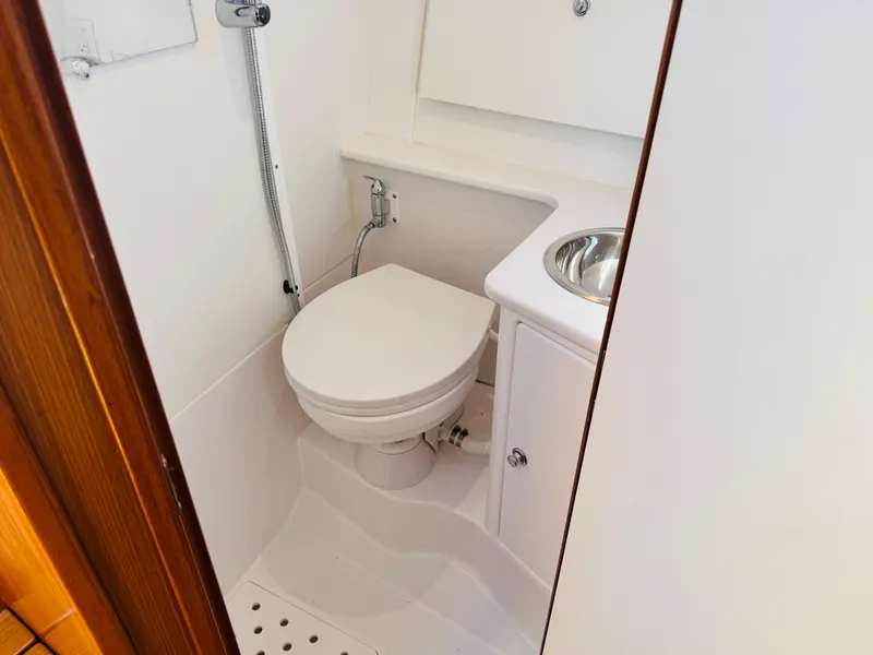 Slide: The Image of Compact bathroom in 2024 True North 34 Outboard Express boat, featuring toilet and sink. - 33