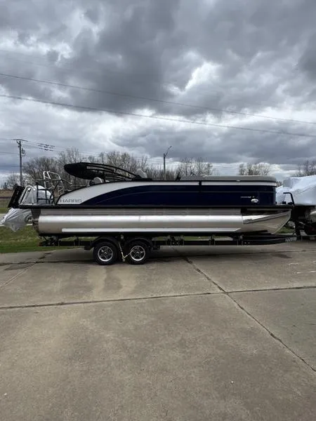 Slide: The Image of 2025 Harris Cruiser 230 pontoon boat on trailer under cloudy sky. - 10