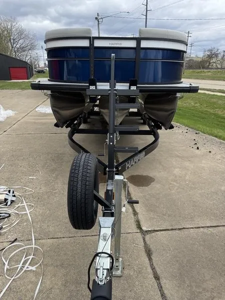 Slide: The Image of 2025 Harris Cruiser 230 pontoon boat on trailer, parked on concrete driveway. - 3