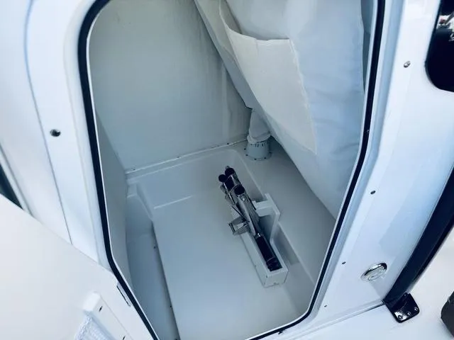 Slide: The Image of 2024 Sea Hunt Ultra 239 SE boat storage compartment with white interior and secure latch. - 15