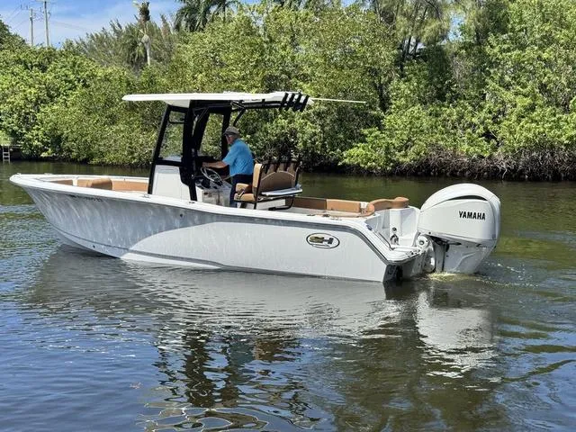 Slide: The Image of 2024 Sea Hunt Ultra 239 SE boat cruising on a calm river with lush greenery. - 21