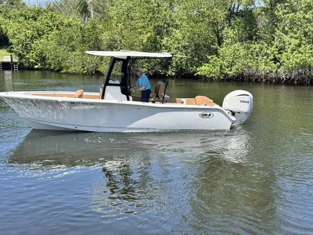 Slide: The Image of 2024 Sea Hunt Ultra 239 SE boat cruising on a calm river with lush greenery. - 22