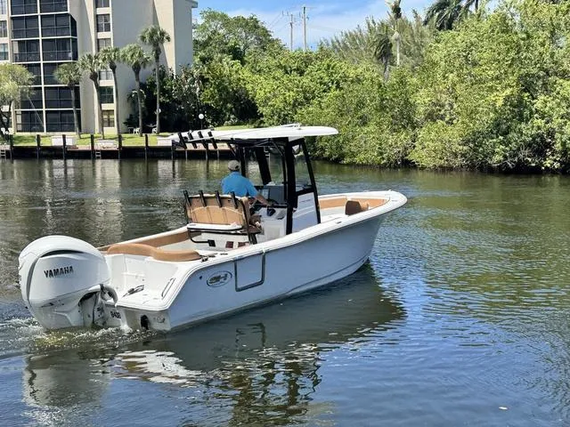 Slide: The Image of 2024 Sea Hunt Ultra 239 SE boat cruising on a calm river with lush greenery. - 24
