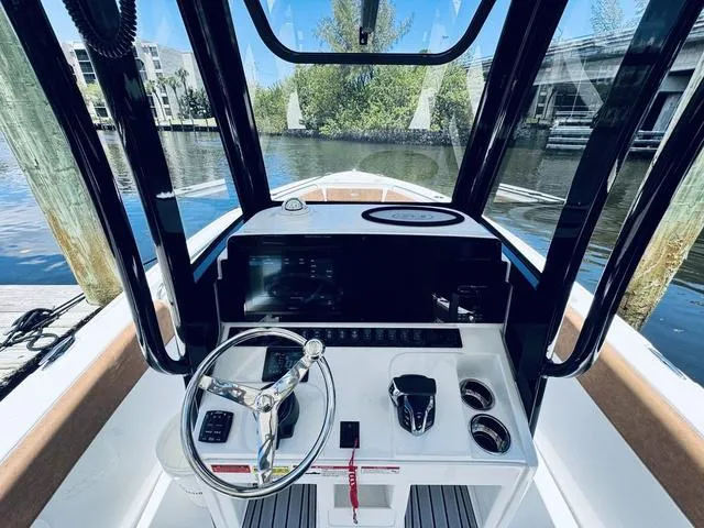 Slide: The Image of 2024 Sea Hunt Ultra 239 SE boat cockpit with steering wheel and controls, docked by the water. - 31