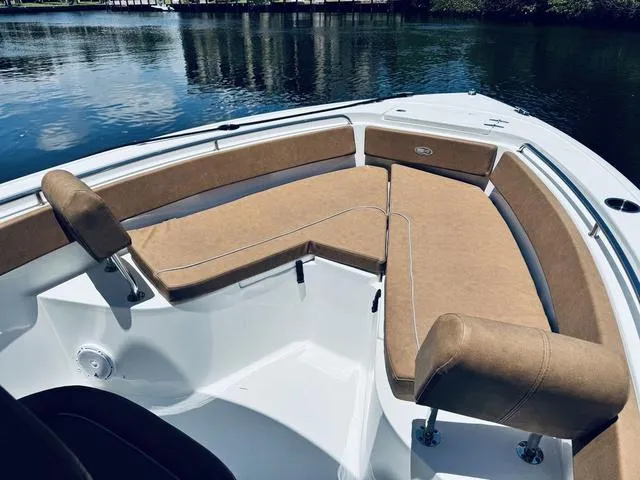 Slide: The Image of 2024 Sea Hunt Ultra 239 SE boat with tan seating, on calm water. - 6