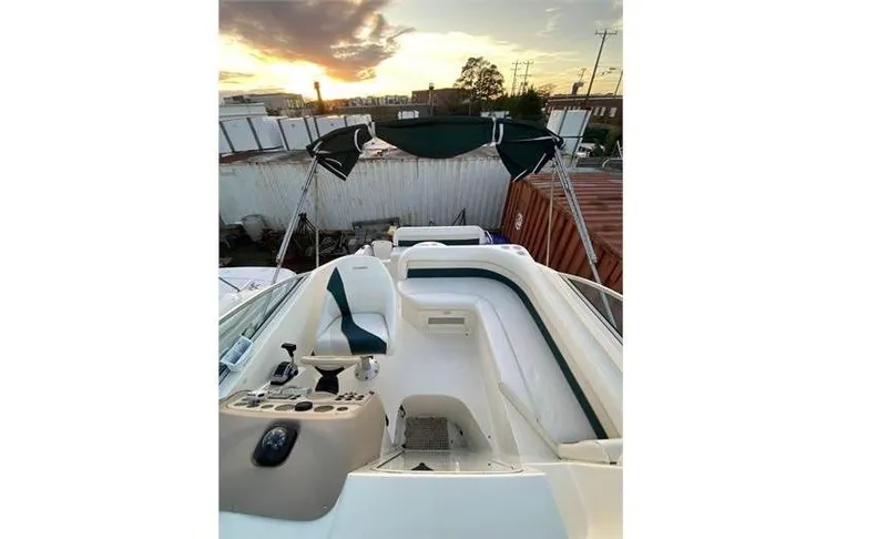 Slide: The Image of 1997 Rinker 266 Fiesta Vee boat interior with seating and helm, sunset in background. - 11
