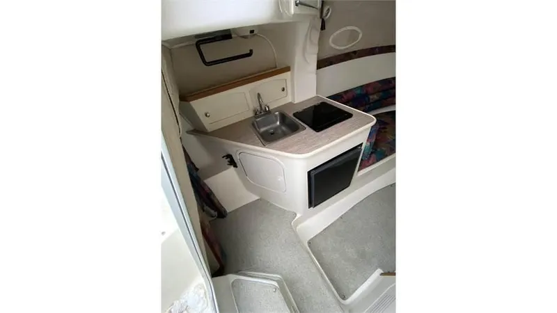 Slide: The Image of 1997 Rinker 266 Fiesta Vee boat interior with kitchenette and seating area. - 14