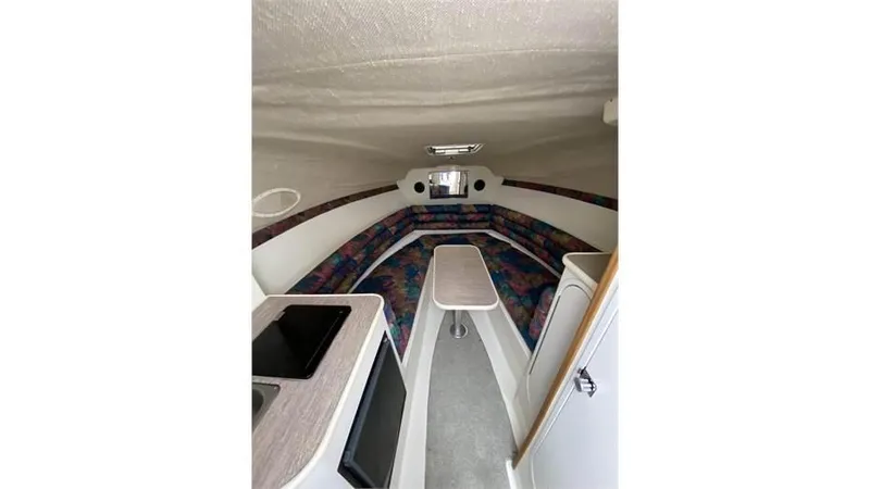 Slide: The Image of Interior of 1997 Rinker 266 Fiesta Vee boat, featuring seating and compact kitchenette. - 15