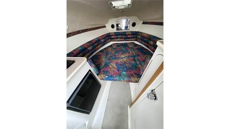 Slide: The Image of 1997 Rinker 266 Fiesta Vee cabin interior with colorful seating and compact kitchen area. - 17