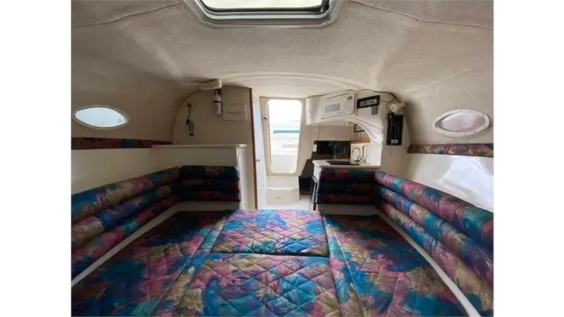 Slide: The Image of 1997 Rinker 266 Fiesta Vee cabin interior with colorful seating and compact kitchenette. - 19