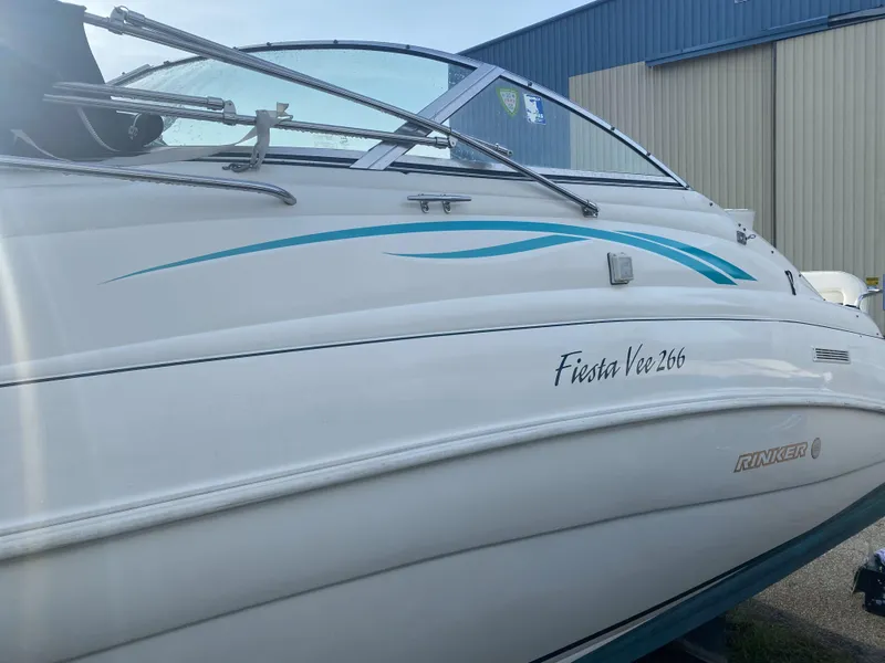 Slide: The Image of 1997 Rinker 266 Fiesta Vee boat with blue accents, docked near a building. - 3