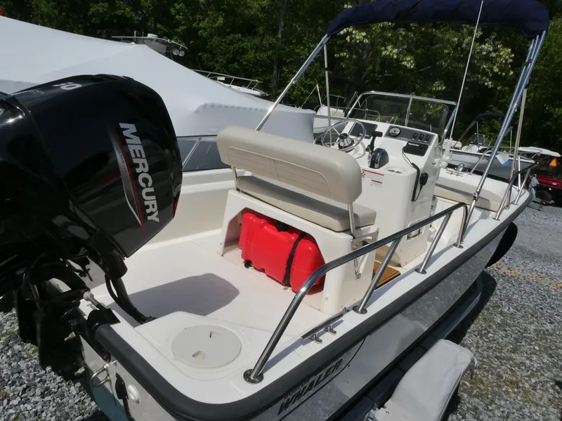 Slide: The Image of 2022 Boston Whaler 150 Montauk boat with Mercury engine, docked outdoors. - 2