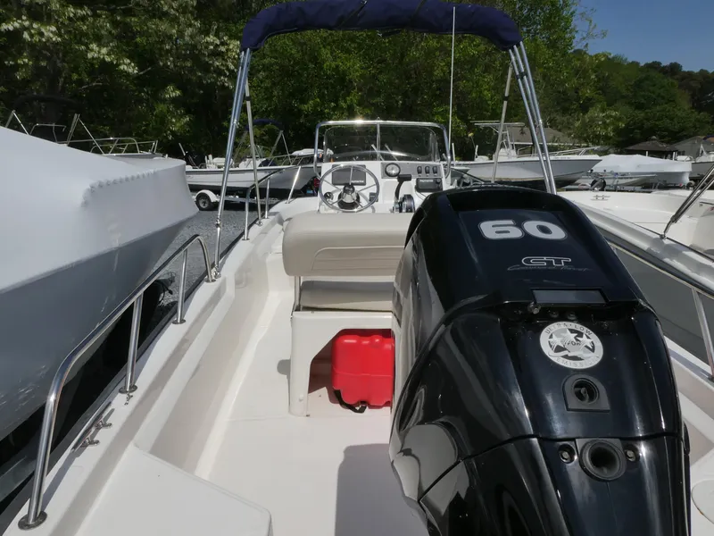 Slide: The Image of 2022 Boston Whaler 150 Montauk boat with 60 HP engine, docked outdoors. - 3
