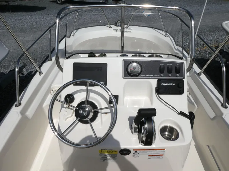 Slide: The Image of 2022 Boston Whaler 150 Montauk boat console with steering wheel and controls. - 6