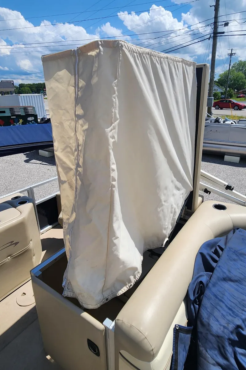 Slide: The Image of 2014 Bennington 20 SF boat with privacy curtain, beige interior, and clear blue sky. - 12