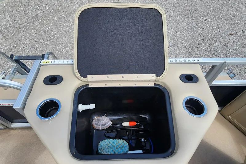 Slide: The Image of 2014 Bennington 20 SF boat storage compartment with open lid and various items inside. - 13