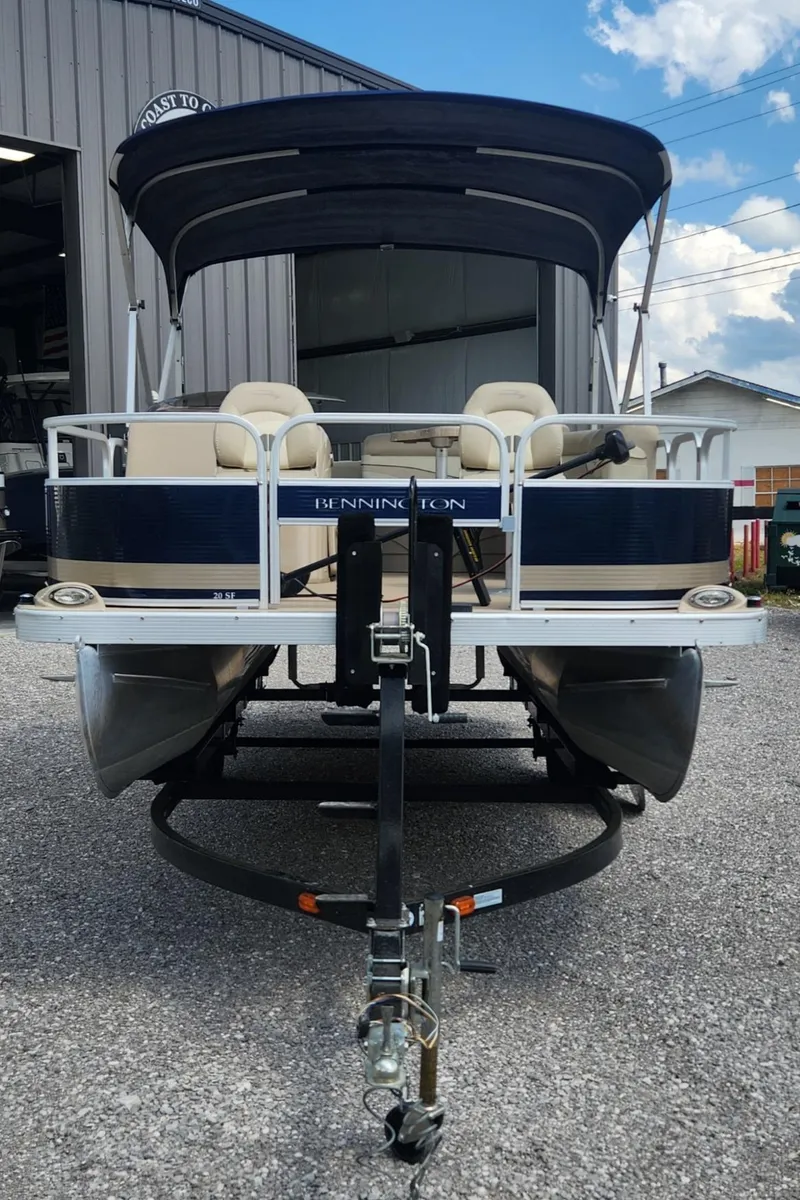 Slide: The Image of 2014 Bennington 20 SF pontoon boat on trailer, parked outdoors near a building. - 2