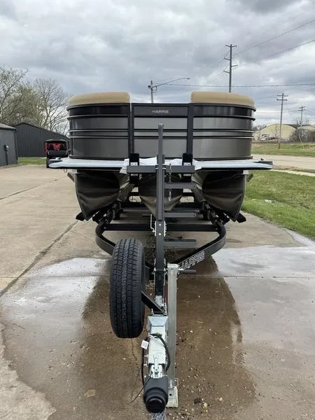 Slide: The Image of 2025 Harris Sunliner 230 pontoon boat on trailer, parked outdoors under cloudy skies. - 3