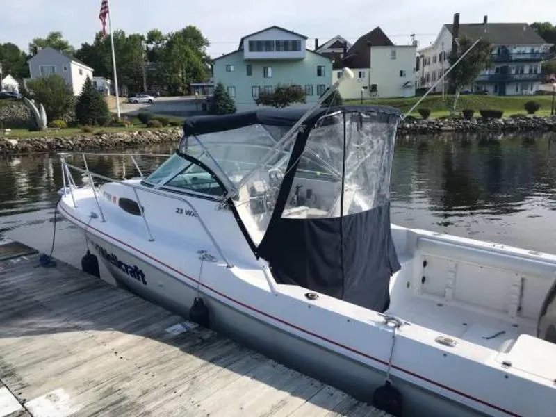 Slide: The Image of 1998 Wellcraft 23 Walkaround boat docked by a scenic waterfront. - 0