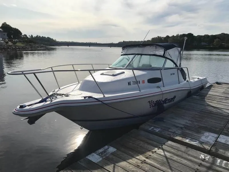 Slide: The Image of 1998 Wellcraft 23 Walkaround boat docked on a calm lake under a cloudy sky. - 2